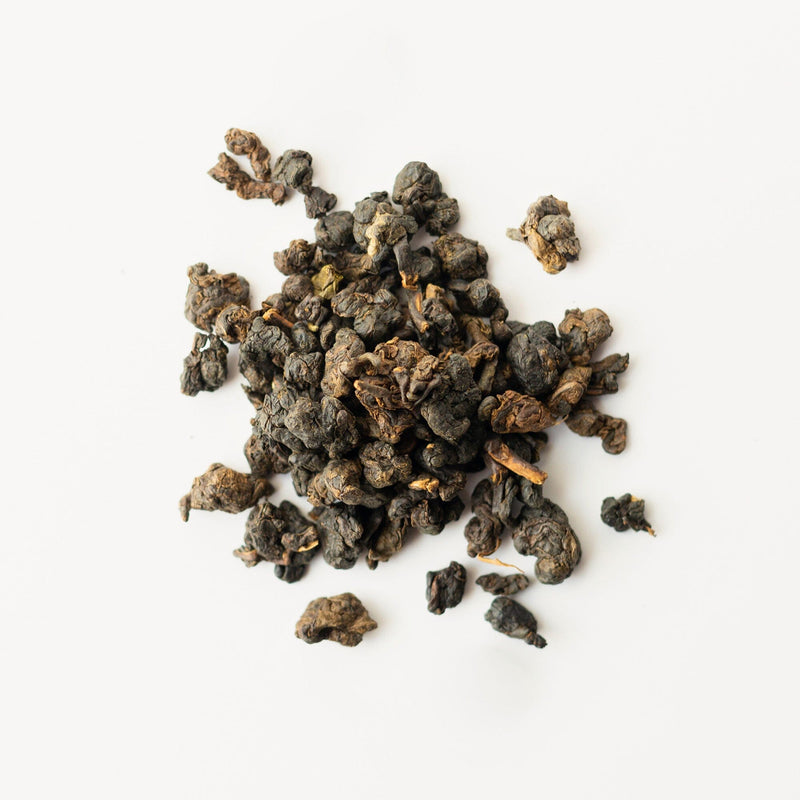 Loose-leaf oolong tea from Rishi Tea & Botanicals is beautifully scattered on a pristine white background, evoking a deep infusion.