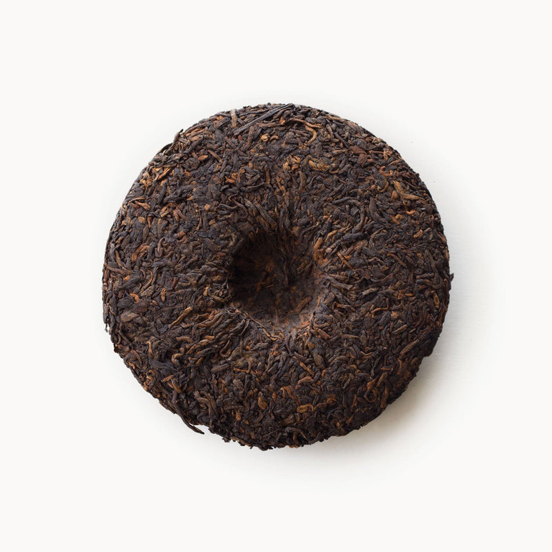 A Pu’er Tea Cake on a white background by Rishi Tea & Botanicals.