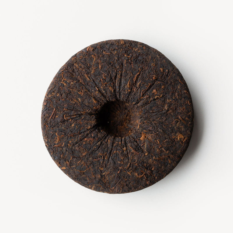 An image of a Wa Shan Shu Pu'er Cake Vintage 2018 from Rishi Tea & Botanicals on a white surface.
