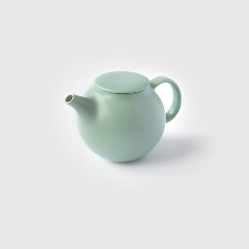 The Kinto USA, Inc matte pastel green Pebble teapot features a simple design with a rounded body, drip-free spout, and loop handle, all set against a plain white background.