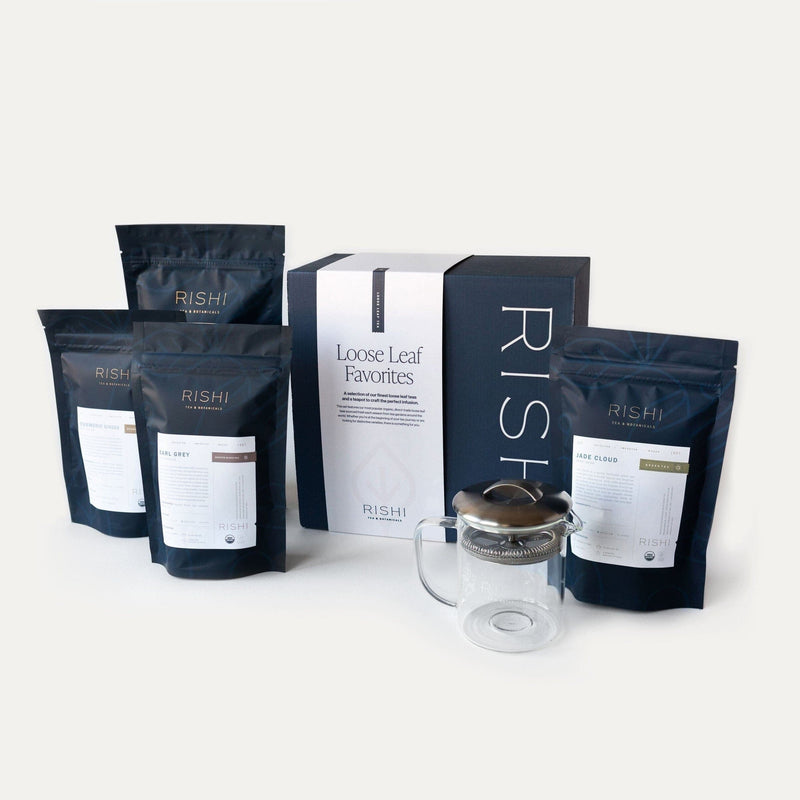 The Loose Leaf Tea Favorites Gift Set from Rishi Tea & Botanicals includes four loose leaf tea bags, a Simple Brew teapot, and is elegantly packaged in a black and white box. This charming set makes an ideal gift for tea lovers and enhances any brewing experience, showcased beautifully on a white background.